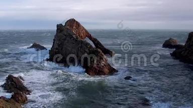 在一个秋天的暴风雨午后，汹涌的海浪拍打着苏格兰的海岩堆。